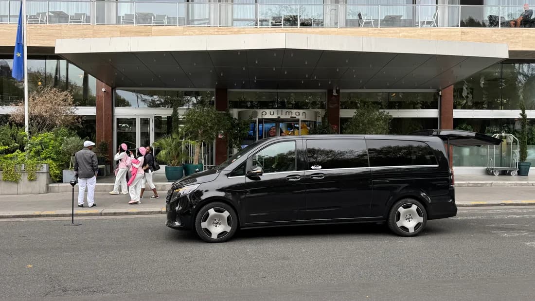 Black Mercedes premium van outside a hotel, supplied by Obrigado Transports